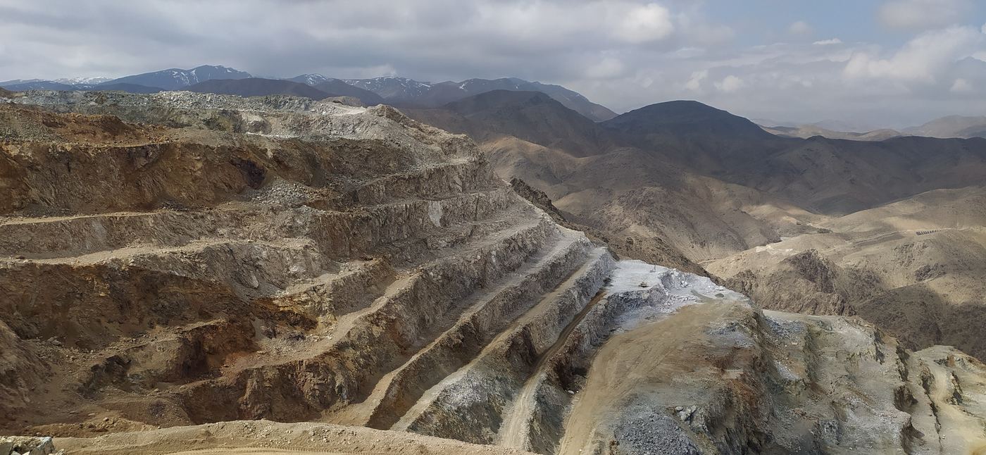Terraced open-pit mine benches with mountains in the distance